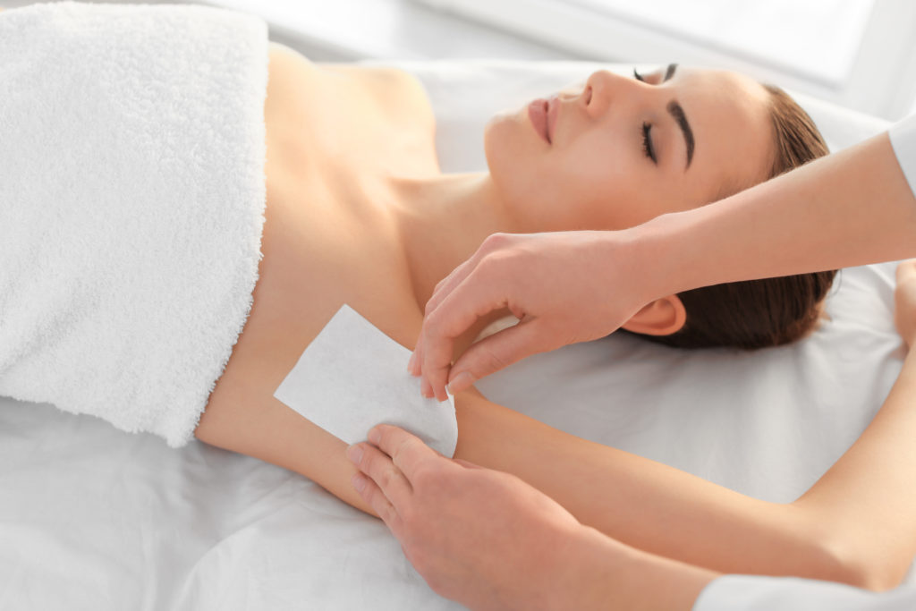 Beautician waxing female armpits in spa center at The Best Injector